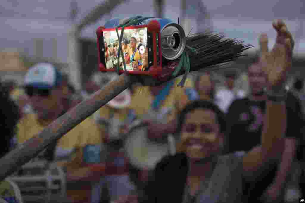 브라질 리우데자네이루에서 열린 &#39;삼바의 날&#39; 축제에서 한 주민이 빗자루와 맥주캔, 고무밴드로 만든 셀피스틱을 들고 있다.