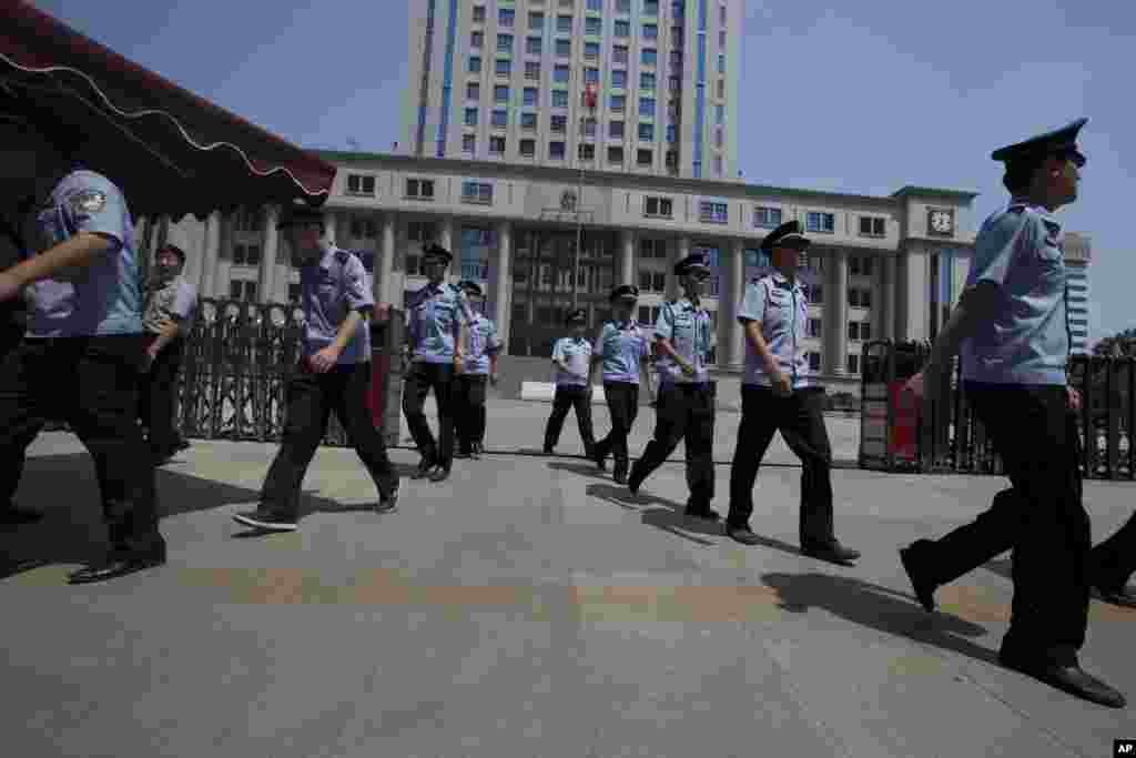 Chinese police officers march out of the Jinan Intermediate People's Court in Jinan in eastern China's Shandong province, August 21, 2013.