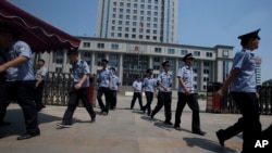 FILE - Chinese police officers march out of the Jinan Intermediate People's Court in Jinan in eastern China's Shandong province, Aug. 21, 2013.