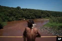 Hayo, chief of the Pataxo Ha-ha-hae indigenous community, stands over the Paraopeba River on a rail bridge near his village in Brumadinho, Brazil, Jan. 29, 2019.