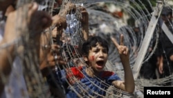 An Egyptian boy peers out of barbed wire during a protest in front of the Supreme Constitutional Court in Cairo, Egypt, Thursday June 14, 2012.