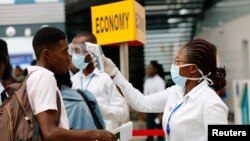 加納首都阿克拉的科託卡國際機場裡一名醫務人員檢測旅客的體溫以防範新冠肺炎。（2020年1月30日）