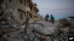 Two boys sit atop a destroyed house in a neighborhood recently retaken by Iraqi security forces from Islamic State militants, in west Mosul, Iraq, April 5, 2017.