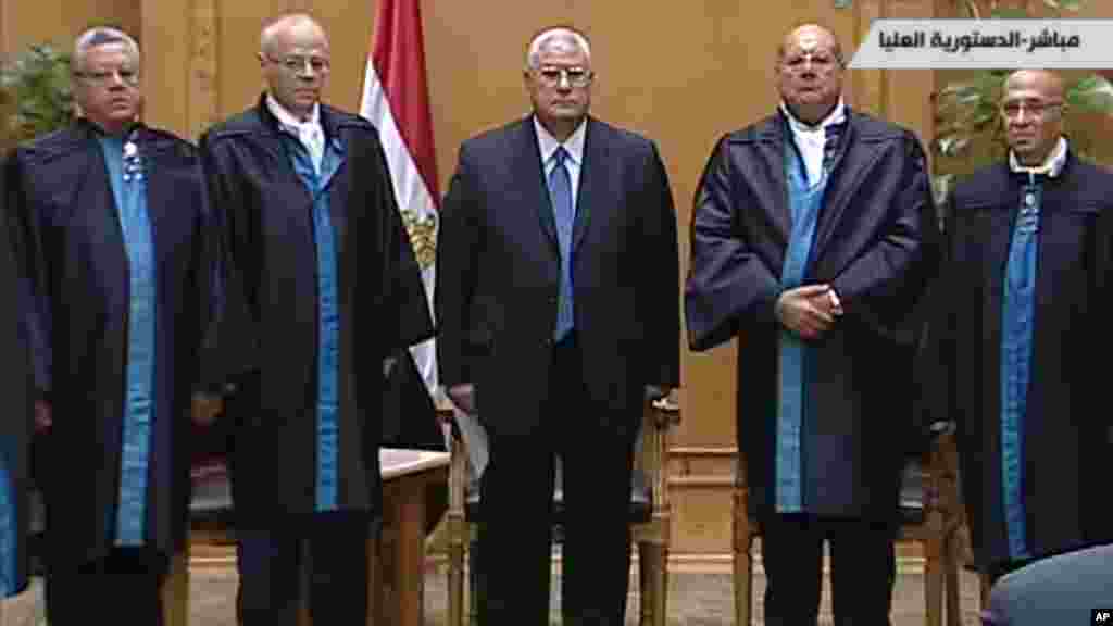 This image made from Egyptian State Television shows Egypt's interim president Adly Mansour, center, standing with judges during a swearing in ceremony in at the constitutional court in Cairo, July 4, 2013.