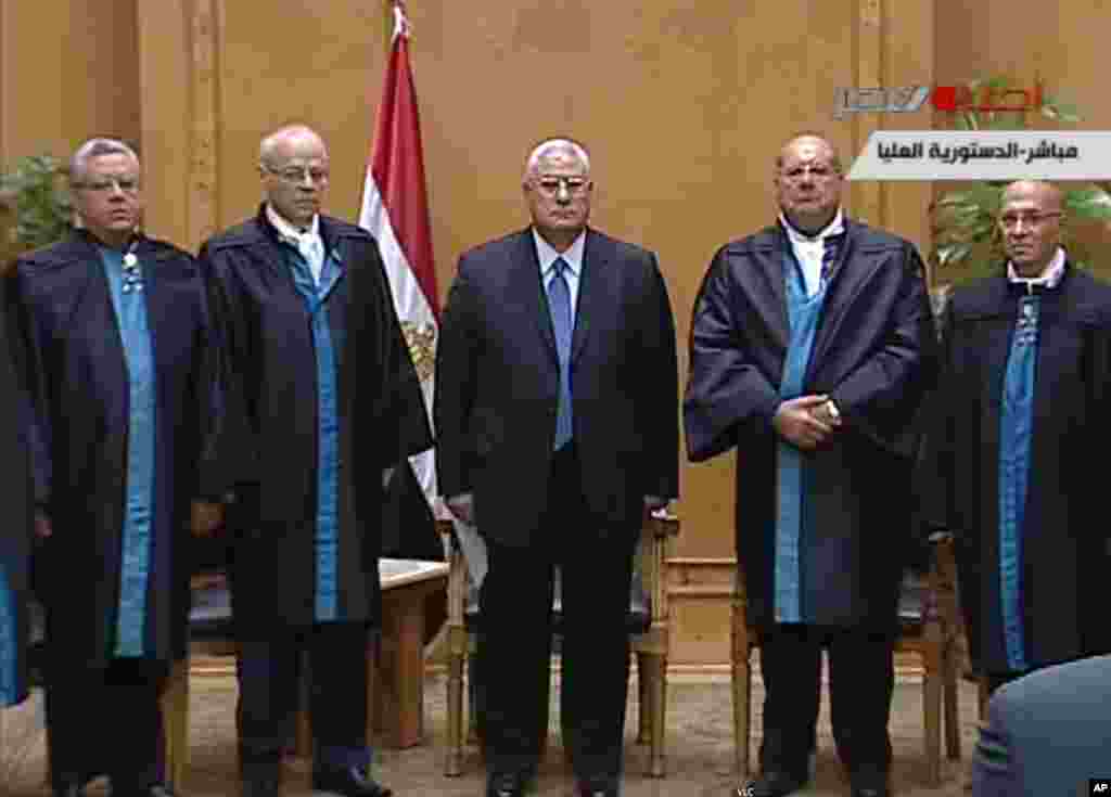 This image made from Egyptian State Television shows Egypt's interim president Adly Mansour, center, standing with judges during a swearing in ceremony in at the constitutional court in Cairo, July 4, 2013.