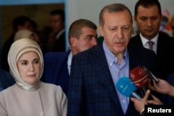 Turkish President Recep Tayyip Erdogan, accompanied by his wife Emine Erdogan, speaks to media after voting in Istanbul, Nov. 1, 2015.
