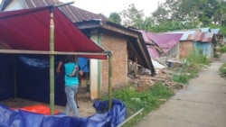 Seorang warga sedang mendirikan tenda terpal di depan rumahnya yang rusak akibat gempa di dusun Petakeang, Kecamatan Tapalang, Sulawesi Barat. Jumat (5/1/2021). (Foto: VOA/Yoanes Litha)