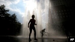 Children play on a fountain during a heat wave