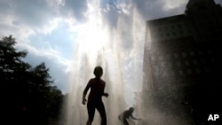 Children play in a fountain during a heat wave.
