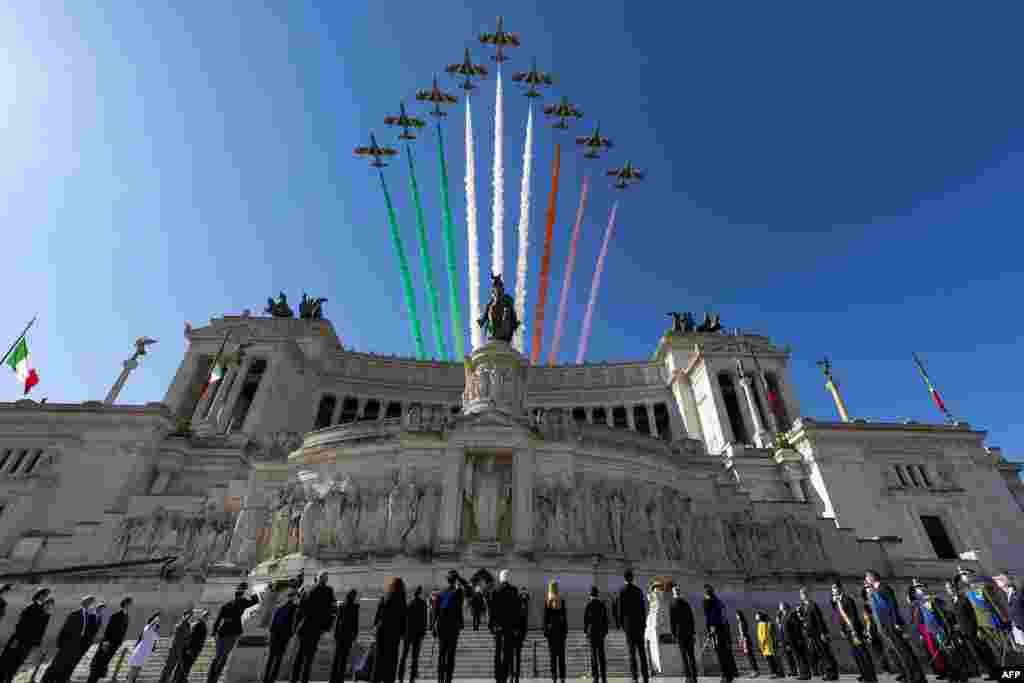 This handout photo by the press office of the Quirinale presidential palace shows the Italian Air Force acrobatic unit flies over the Vittorio Emanuele II National Monument as President Sergio Mattarella (Bottom Rear C) and officials lay a wreath at the tomb of the unknown soldier in Rome as part of Republic Day ceremonies.