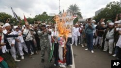 Protesters burn an effigy of U.S. President Donald Trump during a rally outside U.S. Embassy in Jakarta, Indonesia, Monday, Dec. 11, 2017.