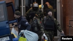 Members of the Ukrainian far-right radical group Right Sector leave their headquarters in Dnipro Hotel as police special forces stand guard in Kyiv, April 1, 2014.