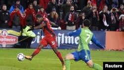 Armando Cooper de Toronto FC frappe la balle devant Cristian Roldan des Seattle Sounders, lors d'un match de MLS, Canada, le 9 décembre 2017. 