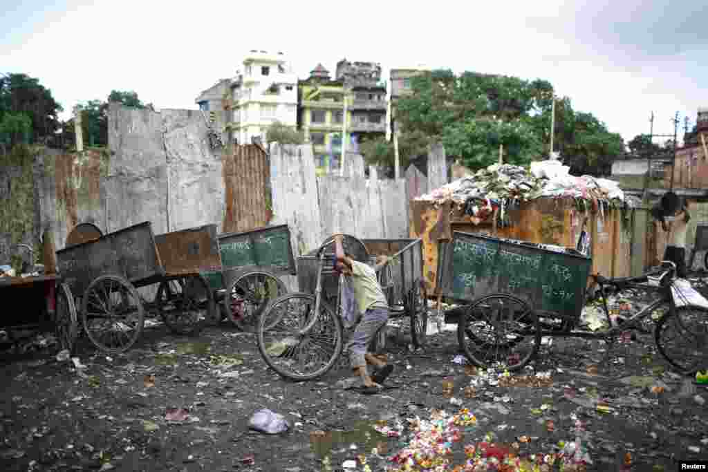 A boy pushes a rickshaw used to carry garbage at the dumping site along the banks of Bishnumati River in Kathmandu, Nepal.