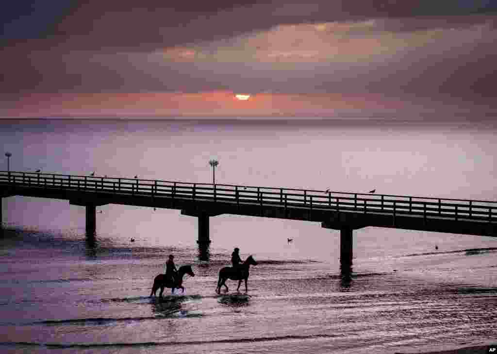 Two young women ride their horses along the shore of the Baltic Sea in Scharbeutz, northern Germany.
