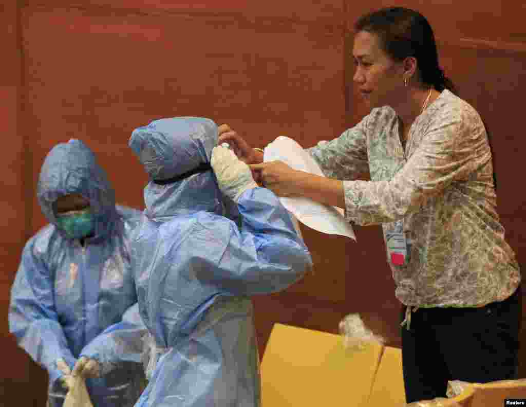 Filipinska bolničarka pomaže kolegi da obuče specijalno zaštitno odelo i upozna se sa opremom tokom demonstracije zaštite od ebole u Istraživačkom institutu za tropsku medicinu u Alabangu, južno od prestonice Manile. 28. oktobar, 2014. 