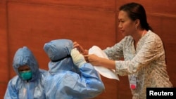 Seorang pekerja kesehatan Filipina membantu koleganya memakai pakaian dan alat-alat pelindung dalam pelatihan menangani Eboladi Alabang, Muntinlupa. 