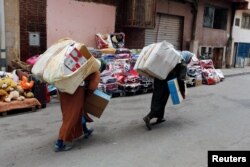 FILE - Moroccan women carry goods after crossing the border from Spain's North African enclave of Melilla into Moroccan settlement of Beni Ansar, in Beni Ansar, Morocco, July 18, 2017.
