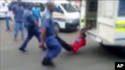 A South African man with his hands tethered to the back of a police vehicle being dragged behind as police hold his legs up and the vehicle apparently drives off, east of Johannesburg, Feb. 26, 2013. The man died of his injuries.