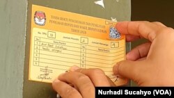 Seorang warga Sleman, DI Yogyakarta menempelkan stiker tanda akurasi data pemilih. Sleman menjadi salah satu kabupaten yang melaksanakan PIlkada 2020. (Foto: VOA/Nurhadi Sucahyo)