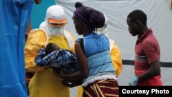 A health worker for Doctors Without Borders / Medecins Sans Frontieres comforts a boy whose mother has died of Ebola. (Photo courtesy of MSF)