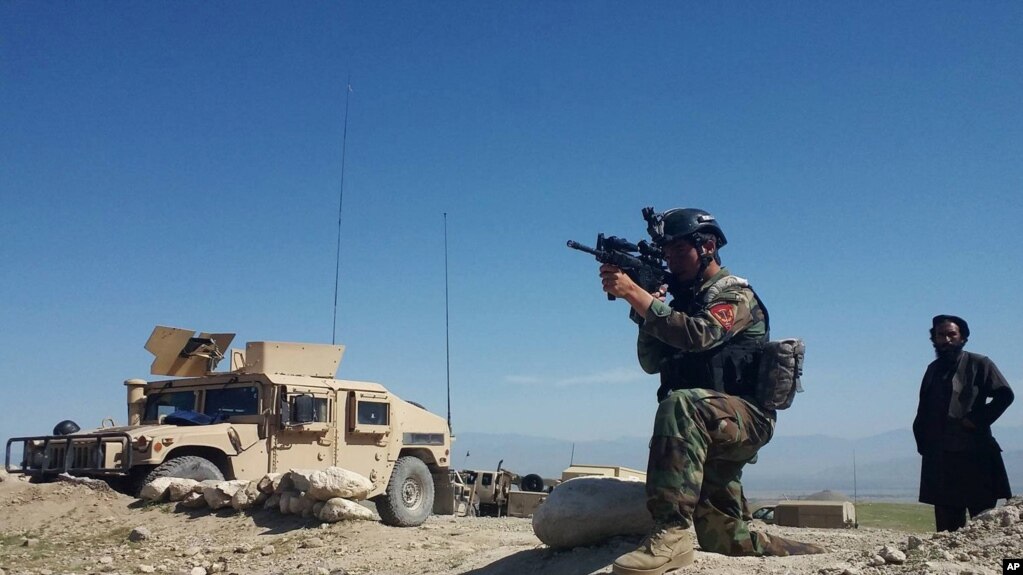 ສະມາຊິກຂອງກອງກຳລັງພິເສດ ອັຟການິສຖານຄົນໜຶ່ງ ກຳລັງແນປືນຂອງລາວ ໃນຂະນະທີ່ລາວ ສັງເກດເບິ່ງ ພວກສັດຕູ ໃນເມືອງ Achin, ແຂວງ ນັນກາຮາ. ພາກຕາເວັນອອກຂອງ ອັຟການິສຖານ. 14 ເມສາ, 2017.