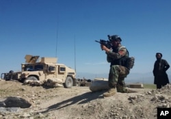 FILE - A member of Afghanistan's special forces points his gun as he observes the enemy lines in Achin district of Nangarhar province, in eastern Afghanistan April 14, 2017.