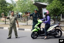 Police in Aceh direct a woman on a motor bike (AP)