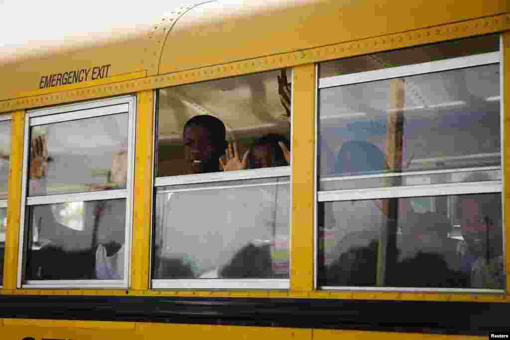 Sebuah bus sekolah dipenuhi anak-anak yang berseru &quot;Tangan di atas, jangan tembak&quot; saat kendaraan tersebut melewati tempat di mana polisi St. Louis Metropolitan sebelumnya menembak seorang pria bersenjata pisau sampai tewas di St. Louis (19/8). (Reuters/Lucas Jackson)