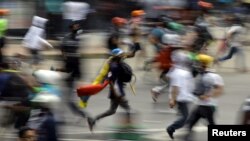 FILE - Demonstrators run during clashes with riot security forces at a protest against Venezuelan President Nicolas Maduro's government in Caracas, Venezuela, May 30, 2017. 