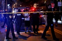 Petugas polisi menahan seorang pria saat otoritas lokal memberlakukan jam malam mulai pukul 8 malam, saat perayaan liburan musim semi, di tengah pandemi COVID-19, di Miami Beach, Florida, AS, 20 Maret 2021. (REUTERS / Marco Bello)