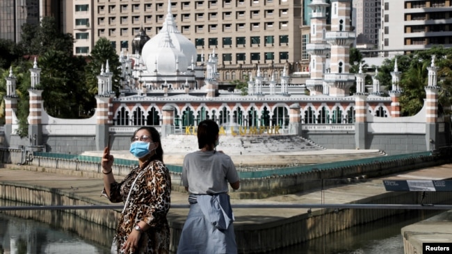 Dua orang turis yang memakai masker tampak menikmati suasana di Kuala Lumpur, Malaysia (foto: ilustrasi).