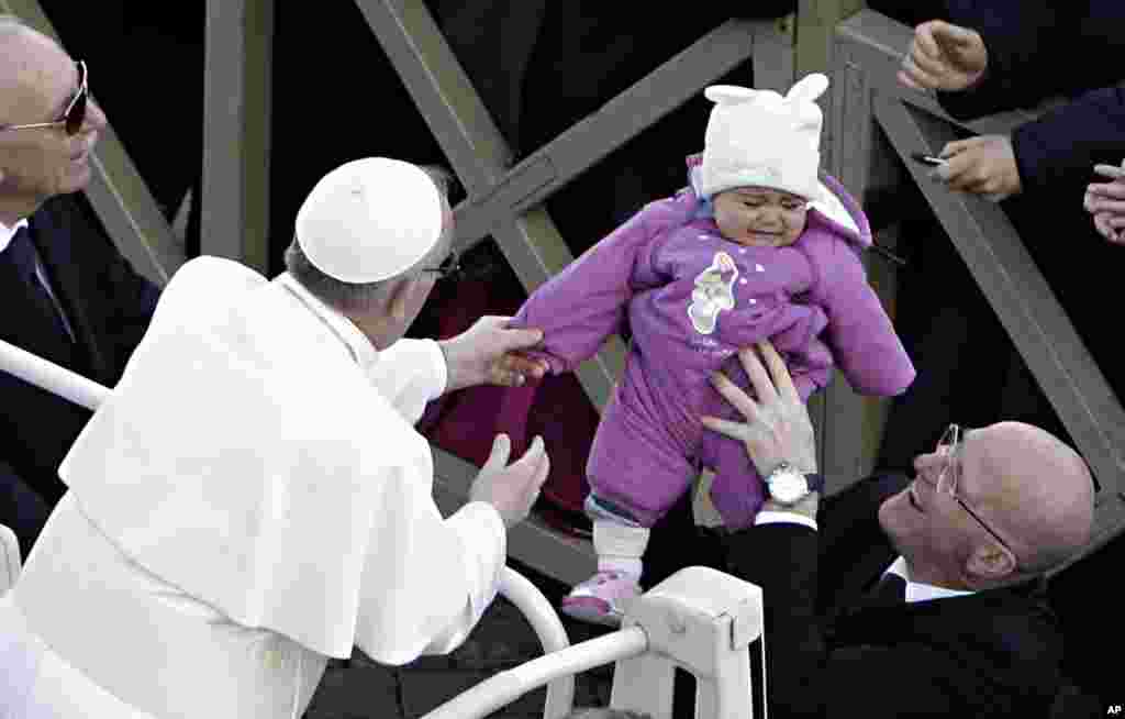 Pope Francis reaches out for a child in Saint Peter's Square at the Vatican, March 19, 2013.