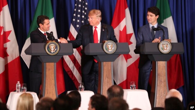 FILE - Mexico's President Enrique Pena Nieto, left, shakes hands with President Donald Trump as Canada's Prime Minister Justin Trudeau looks on as they prepare to sign a new United States-Mexico-Canada Agreement.
