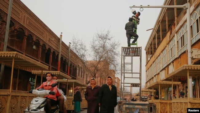 Men install a camera in a shopping street in the old town of Kashgar, Xinjiang Uighur Autonomous Region, China, March 23, 2017.