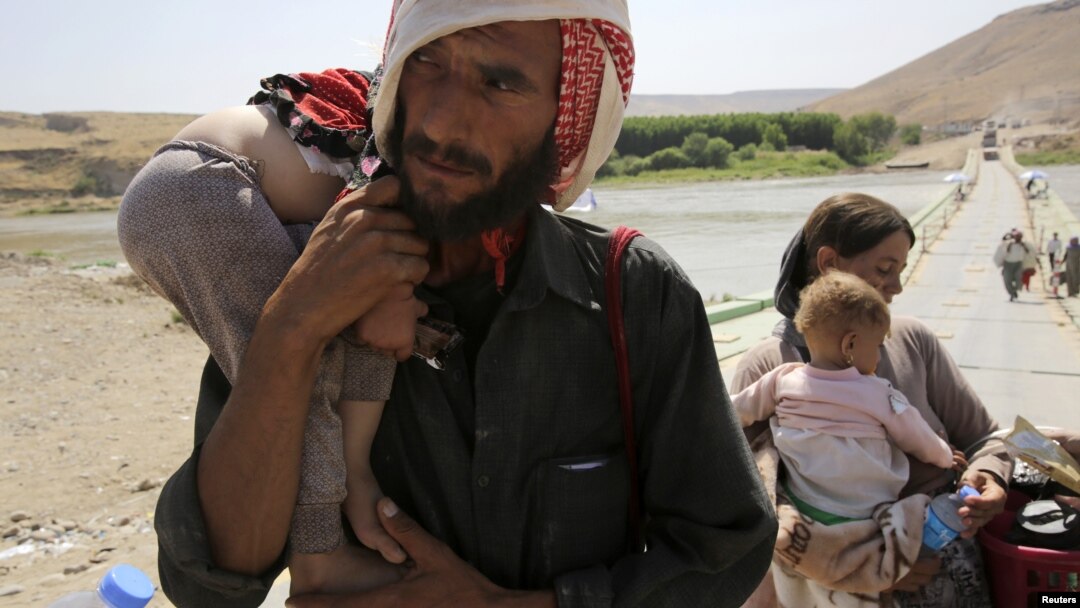 A man and his wife from the minority Yazidi sect, fleeing the violence in the Iraqi town of Sinjar, carry their children as they re-enter Iraq from Syria at the Iraqi-Syrian border crossing in Fishkhabour, Dohuk province, August 14, 2014.