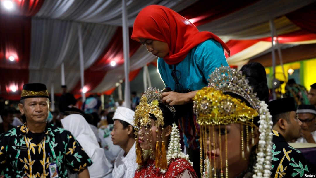 Seorang mempelai perempuan sedang dipasang hiasan kepala saat menghadiri pernikahan masal yang diadakan oleh Pemprov DKI Jakarta sebagai bagian perayaan Tahun Baru di Jakarta, 31 Desember 2017. (REUTERS/Darren Whiteside) 