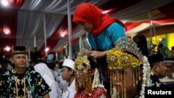 Seorang mempelai perempuan sedang dipasang hiasan kepala saat menghadiri pernikahan masal yang diadakan oleh Pemprov DKI Jakarta sebagai bagian perayaan Tahun Baru di Jakarta, 31 Desember 2017. (REUTERS/Darren Whiteside) 