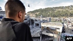 A Palestinian looks at collapsed buildings at the Nur Shams camp for Palestinian refugees, where Israeli raids have been conducted, near the occupied West Bank city of Tulkarm on January 8, 2024.