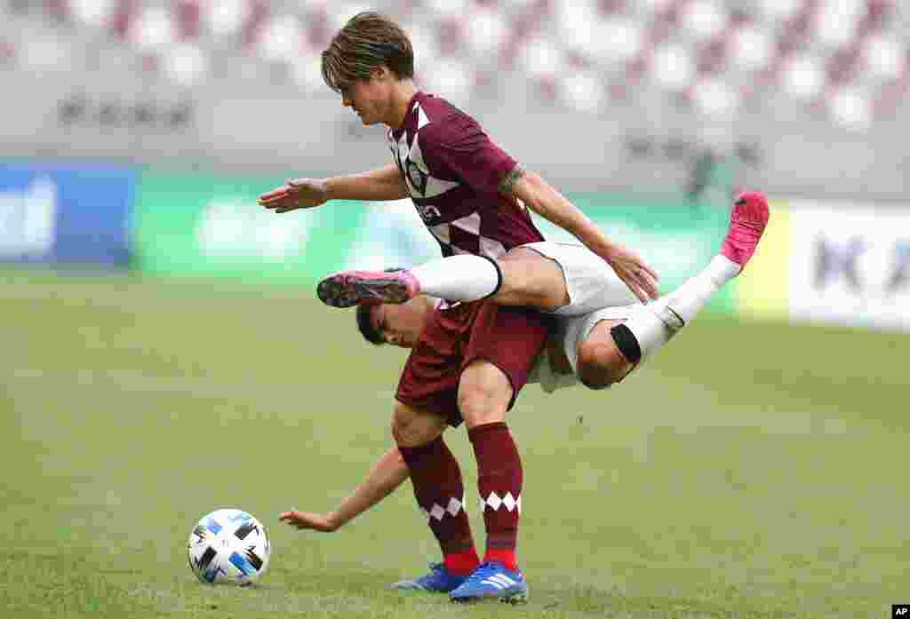 Shanghai SIPG's Li Shenglong and Vissel Kobe's Gotoku Sakai, top, fight for the ball during a round of 16 AFC Champions League match in Doha, Qatar.