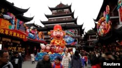 Orang-orang berjalan dengan hiasan raksasa berbentuk seekor babi menjelang Tahun Baru China, Imlek, yang akan datang di Taman Yu Yuan, Shanghai, China, 31 Januari 2019. 