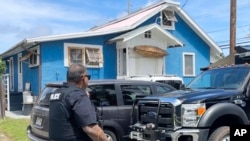 A police officer walks by the home of Ryan Routh, the man accused of an apparent attempt to assassinate Donald Trump, while FBI agents conduct a search inside, Sept. 17, 2024, Kaaawa, Hawaii.