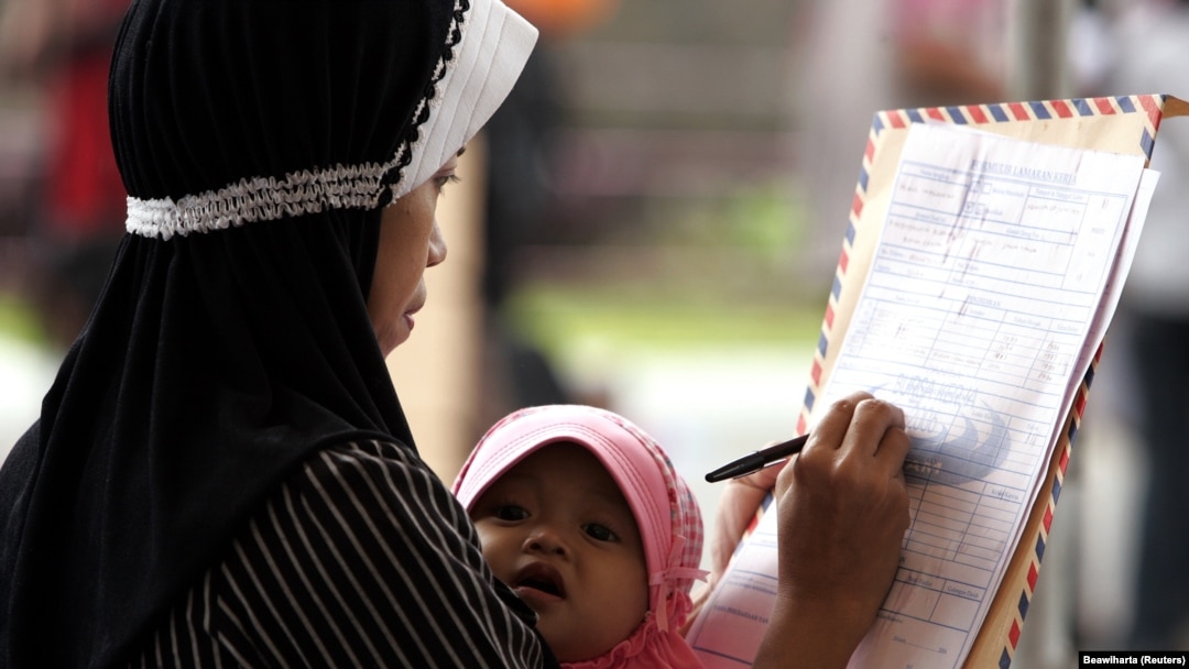Seorang ibu sedang menggendong bayinya saat mengisi formulir lamaran kerja saat job expo di Batam 18 September 2006, sebagai ilustrasi. (Foto: REUTERS/Beawiharta)