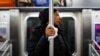 FILE - A subway passenger used a tissue to protect her hand from a pole as COVID-19 concerns drove down ridership in New York, March 19, 2020, Pandemic concerns have eased since then, but the return to "normal" is causing anxiety for some people. 