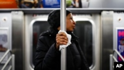 FILE - A subway passenger used a tissue to protect her hand from a pole as COVID-19 concerns drove down ridership in New York, March 19, 2020, Pandemic concerns have eased since then, but the return to "normal" is causing anxiety for some people. 