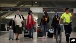 Travelers wear protective masks as a precaution against the coronavirus, at the airport in Mexico City, Mexico, Feb. 28, 2020.