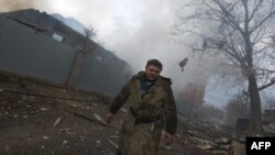 Un combatiente se aleja de varias casas destruidas en el bombardeo en la ciudad de Donetsk, al este de Ucrania.