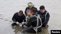 Una mujer es ayudada a salir del agua luego de naufragar con el barco Jianli o Oriental Star en la provincia Hubei de China.