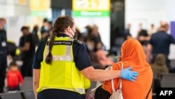 Petugas membantu para pengungsi Afghanistan setibanya di bandara Heathrow, London, 26 Agustus 2021. (Dominic Lipinski / POOL / AFP)