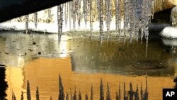 The walls of nearby buildings are reflected in a partially frozen fountain, Jan. 4, 2017, in Tacoma, Washington.